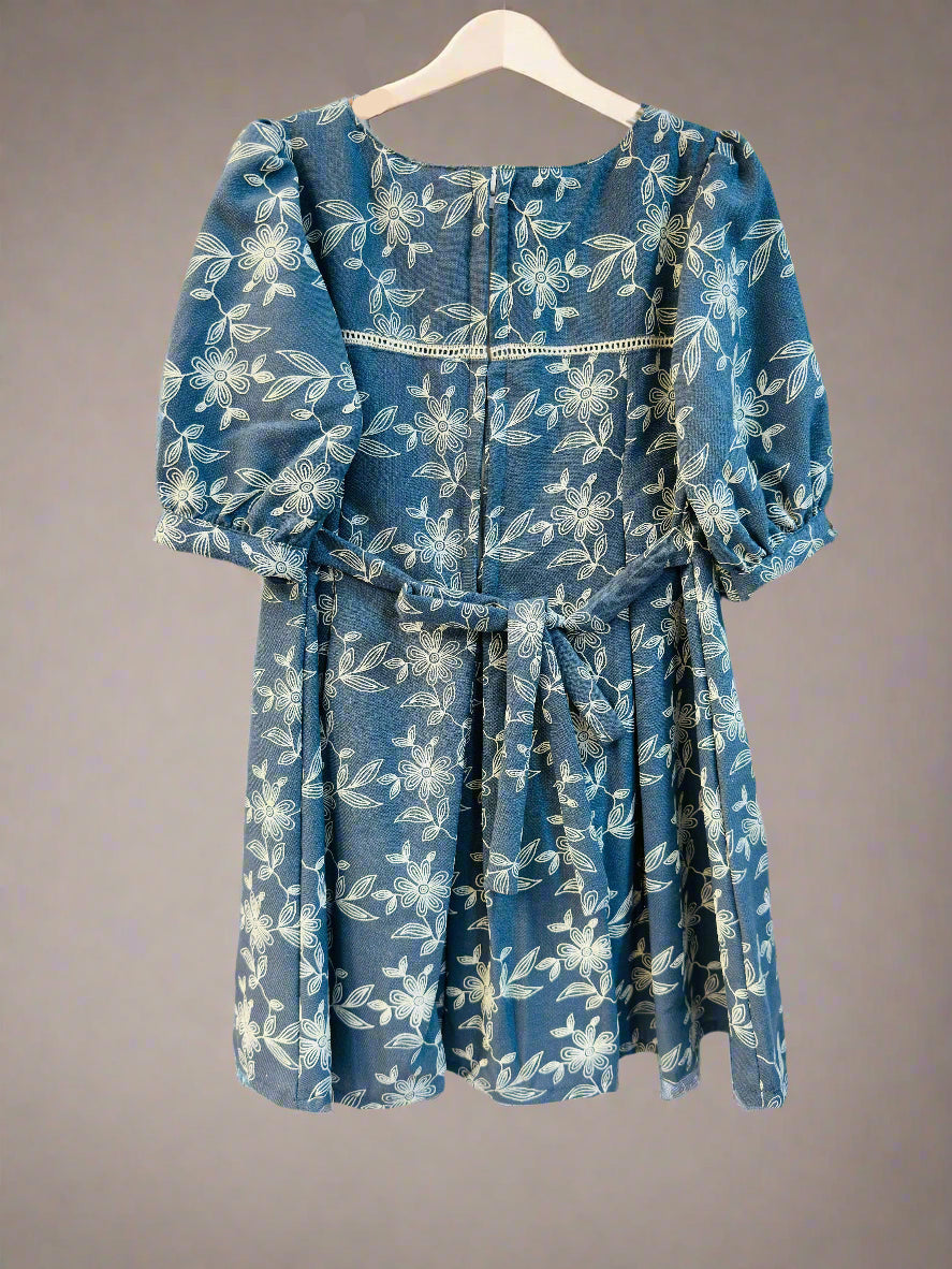Luxe thread girls summer collection dress with floral print and puff sleeves hanging on display